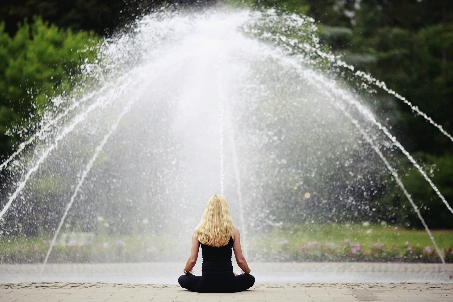 A girl is meditating in front of water fountain