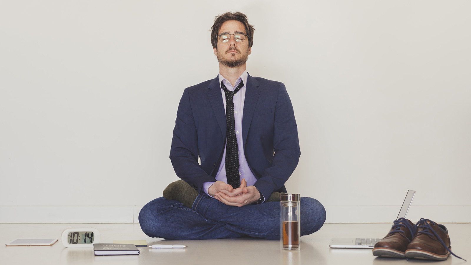 a man sitting cross-legged on the floor, benefiting from meditation after work